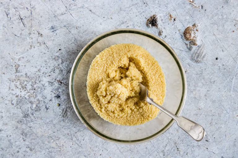 overhead view of how to cook couscous in a clear bowl with spoon inside