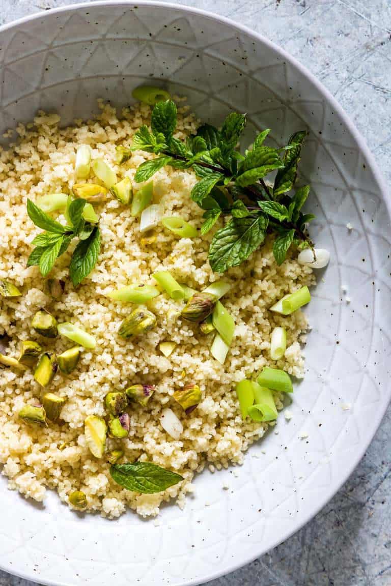 overhead view of how to cook couscous in a bowl with chopped scallions
