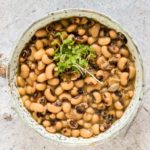 overhead view of black eyed beans in a bowl with greens on top