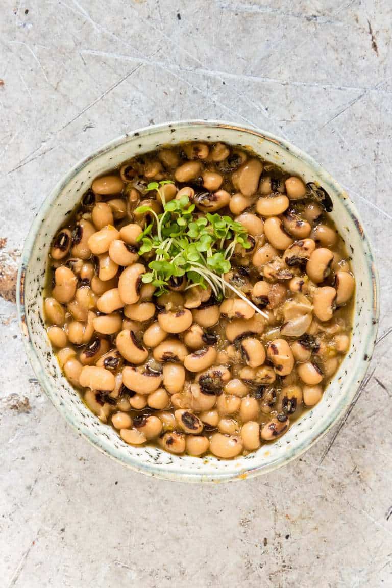 overhead view of black eyed beans in a bowl with greens on top