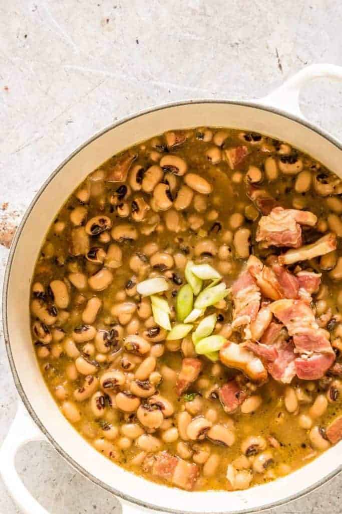 closeup of black eyed beans with bacon on top in pot