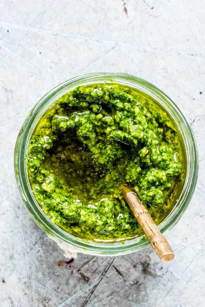 Overhead shot of homemade wild garlic pesto in a jar with a spoon