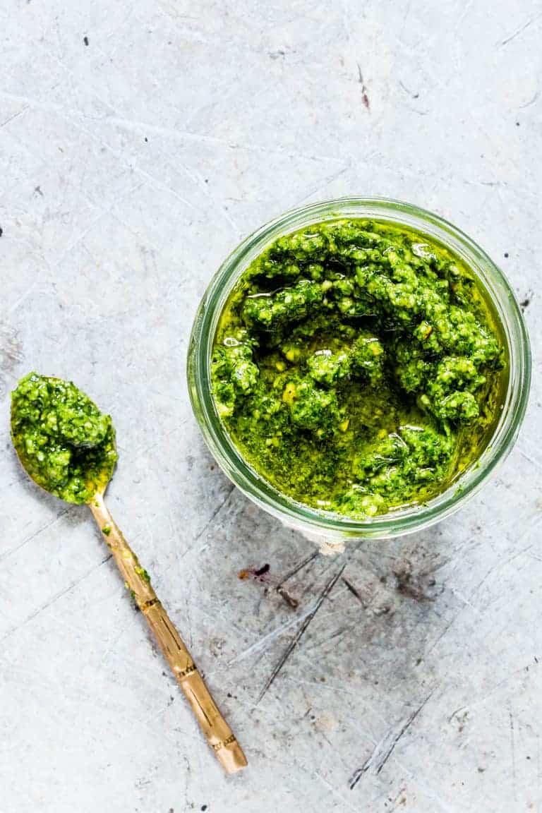 Homemade ramps pesto recipe in a jar with a spoon of pesto next to it