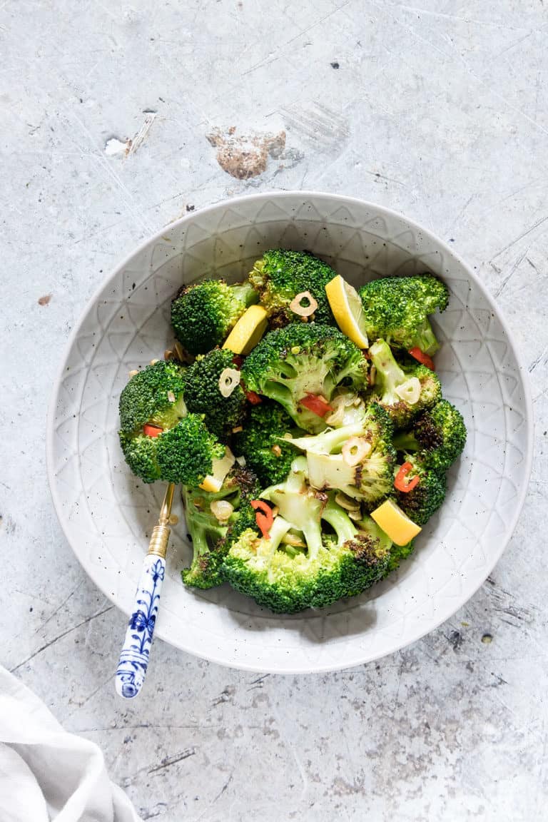 rilled Broccoli in a bowl seasoned with garlic and chilli and lemon with a fork