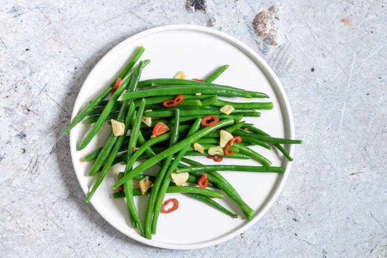 Close up of chilli garlic green beans on a white plate