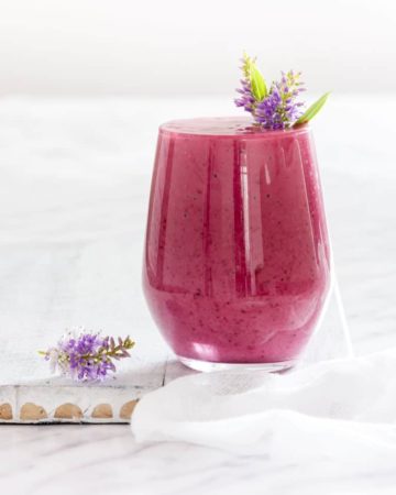 Blackberry Smoothie in a glass with a flower proper in it