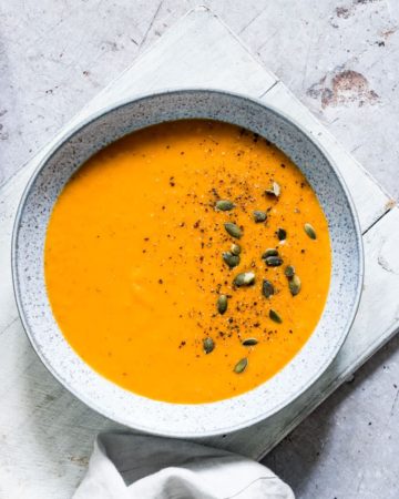 a bowl of instant pot pumpkin soup served with a spoon and cloth napkin