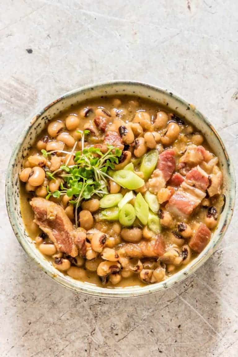 A bowl of Hoppin’ John soup garnished with bacon, spring onion and cress