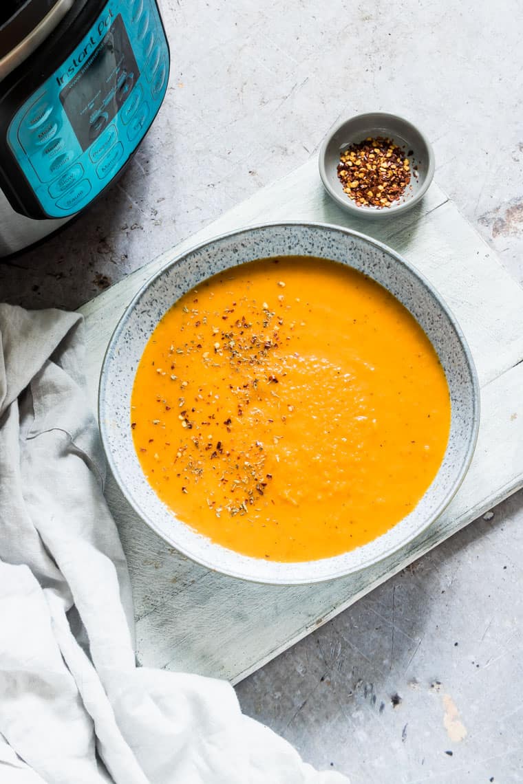 a bowl of instant pot carrot soup next to the instant pot 