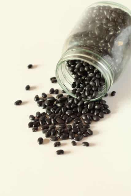 a jar of black beans tipped over and spilling onto the counter