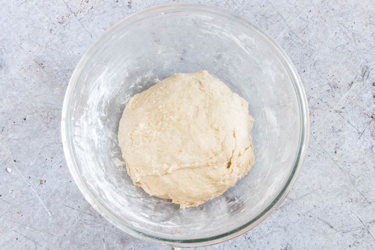 overhead view of cardamom buns dough sitting in a clear glass bowl