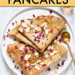 two thin pancakes folded on a plate garnished with slivered almonds and a spoon of honey