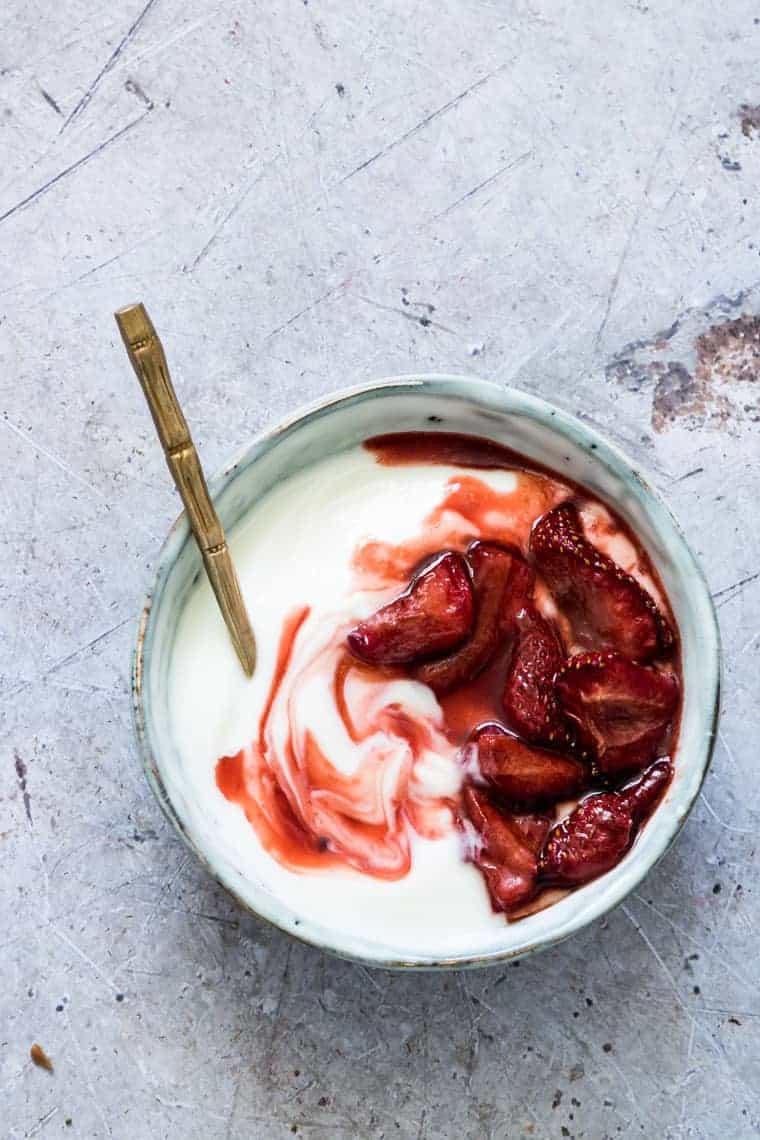 top down view of roasted strawberries swirled into a bowl of yogurt