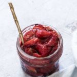 balsamic roasted strawberries in a glass jar with a gold spoon inside and ready to be served