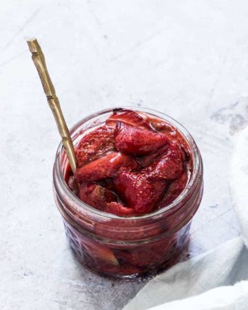 balsamic roasted strawberries in a glass jar with a gold spoon inside and ready to be served
