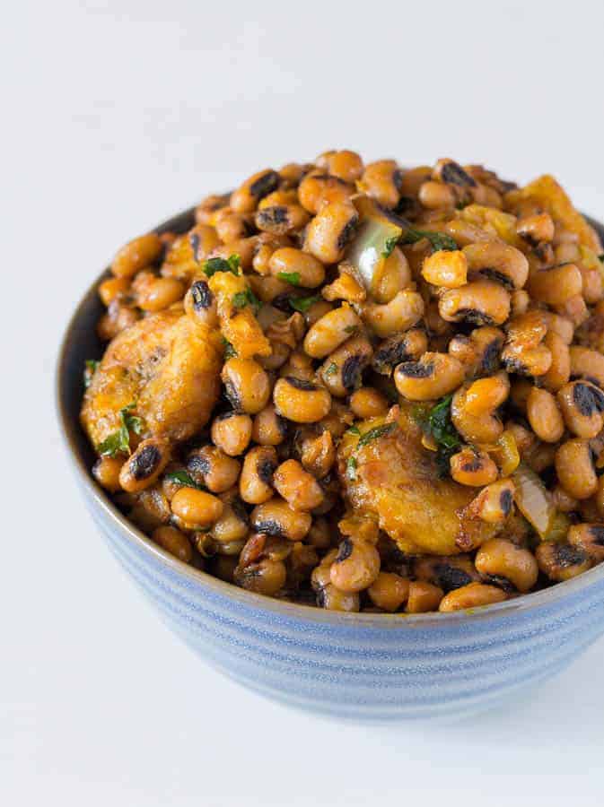 closeup of west african beans and plantains in a blue bowl