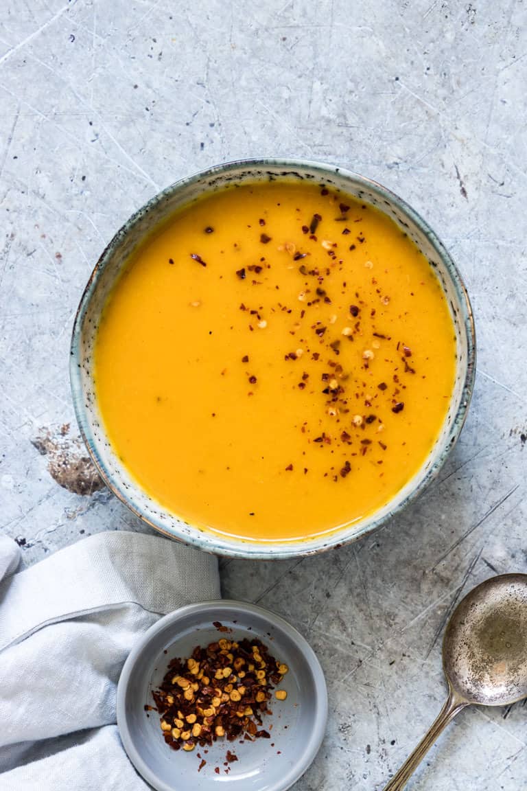 a bowl of kabocha squash soup on a table with a spoon