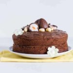 A side on view of a nutella cake with nutella frosting topped with cadbury creme eggs