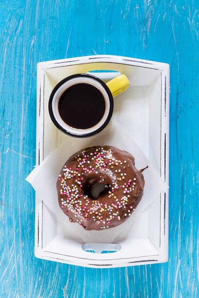 nutella donut on a white napkin on a white platter next to a yellow coffee cup