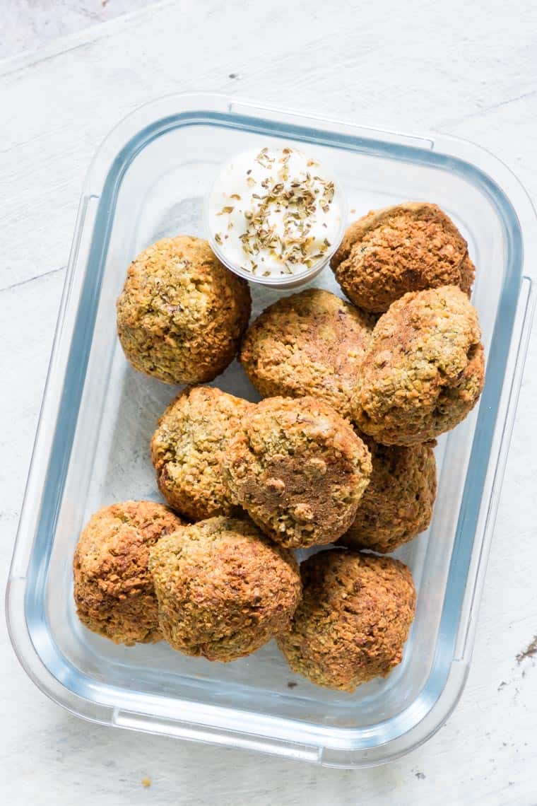 glass meal prep container filled with air fryer falafel and a container of tahini yogurt sauce