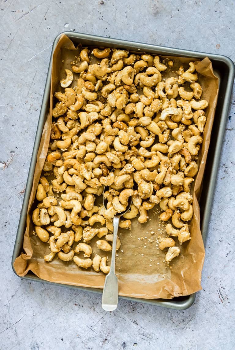 a tray of coconut cashews with a spoon in it