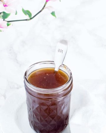 canning jar containing coconut caramel sauce with a spoon sticking out