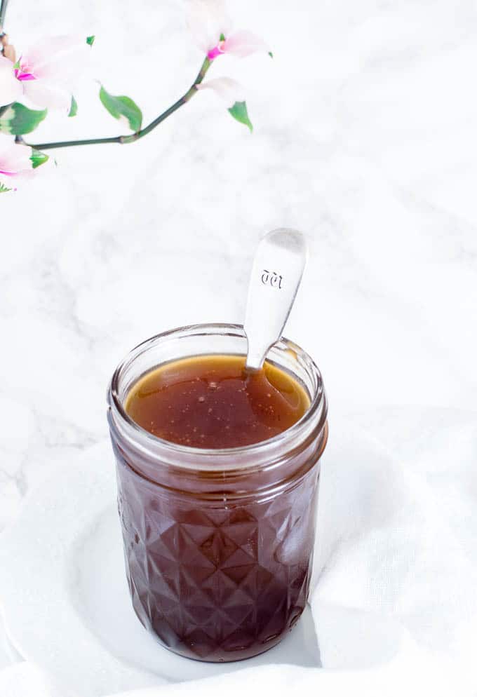 canning jar containing coconut caramel sauce with a spoon sticking out