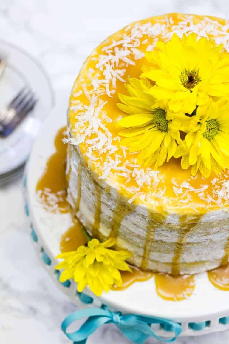 overhead view of mango cake on a cake pan with yellow flowers on top