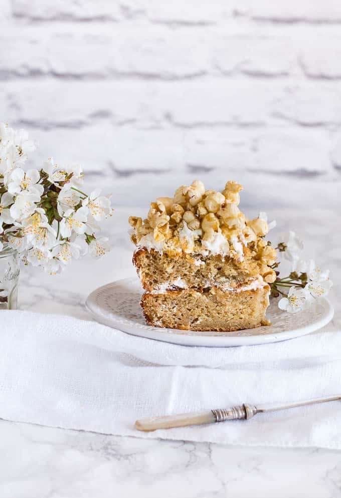 slice of nutmeg plantain cake with caramel popcorn topping on a white plate on a white towel