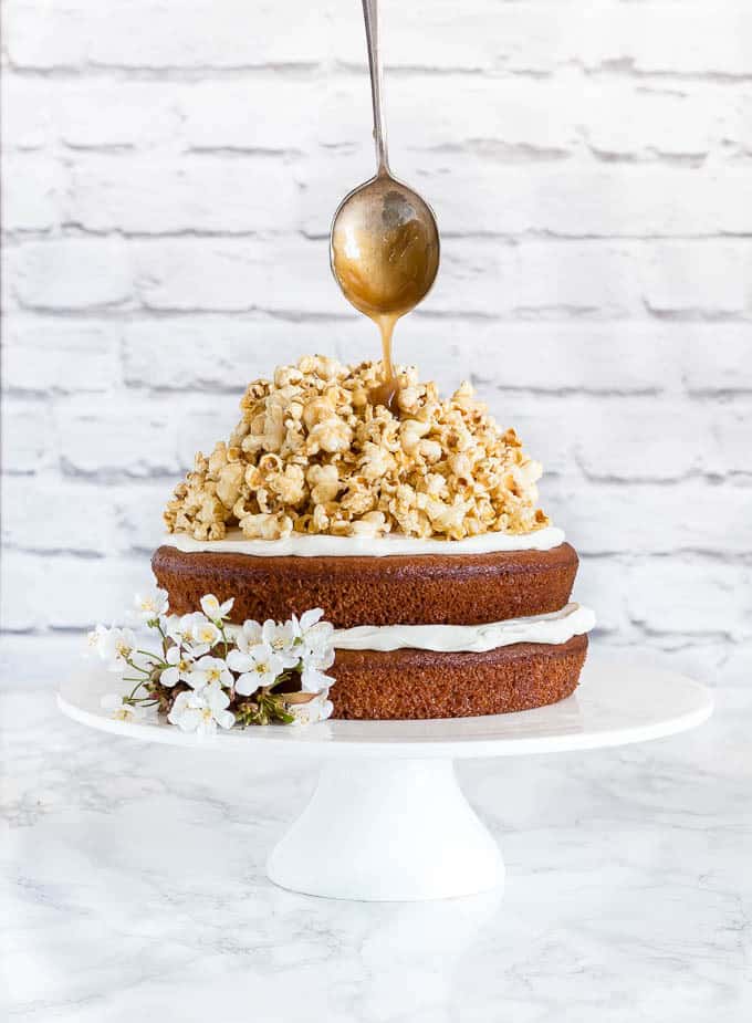 two layer plantain cake with coconut caramel popcorn and a spoon drizzling caramel on top