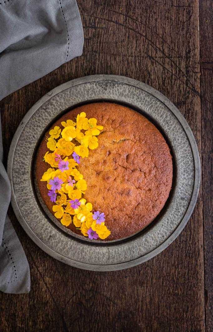 overhead view of cinnamon plantain cake with flowers on the left of the cake