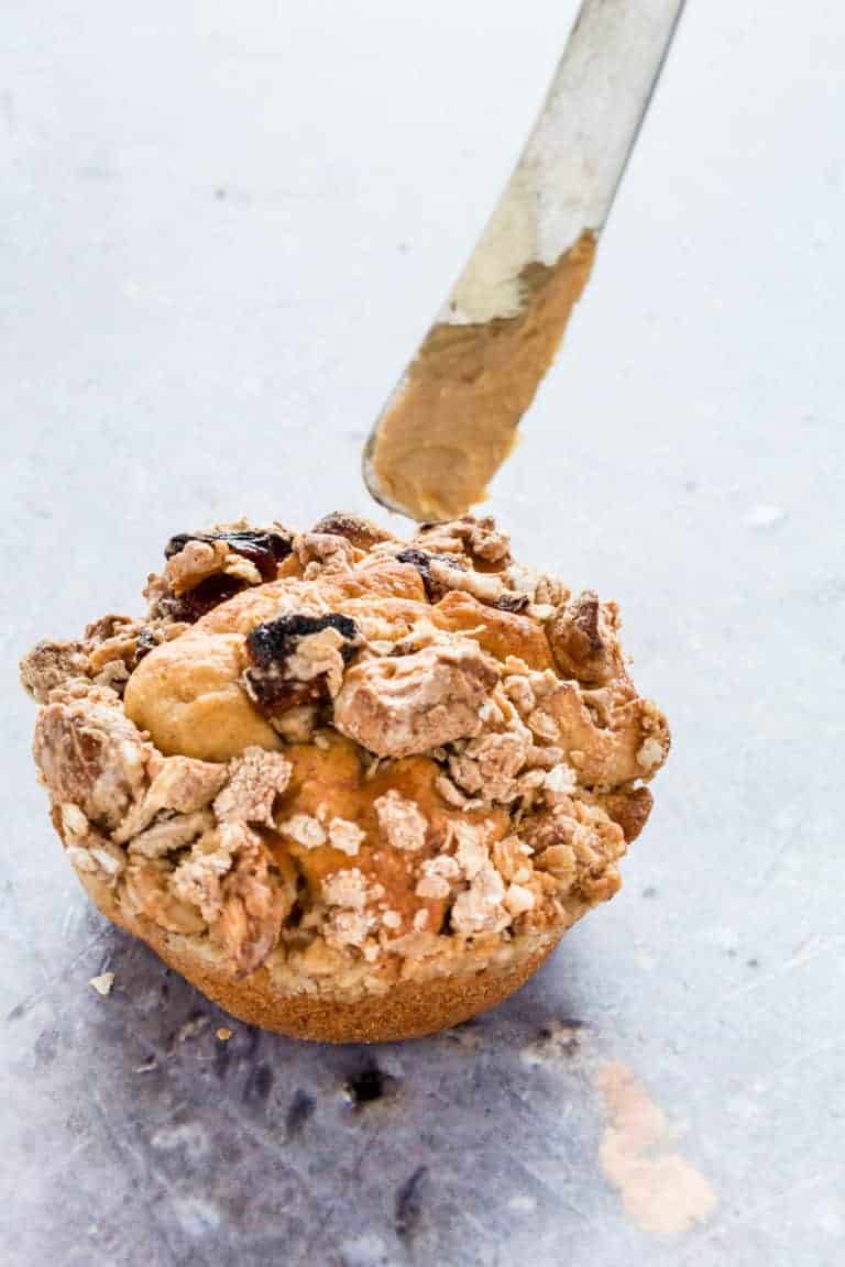 A banana muffin with a knife and some peanut butter