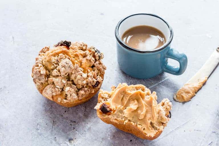  banana muffins spread with peanut butter and some coffee with a knife in the corner