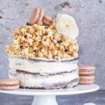 A three layer naked chocolate sponge cake with caramel popcorn decorated with macarons and flowers