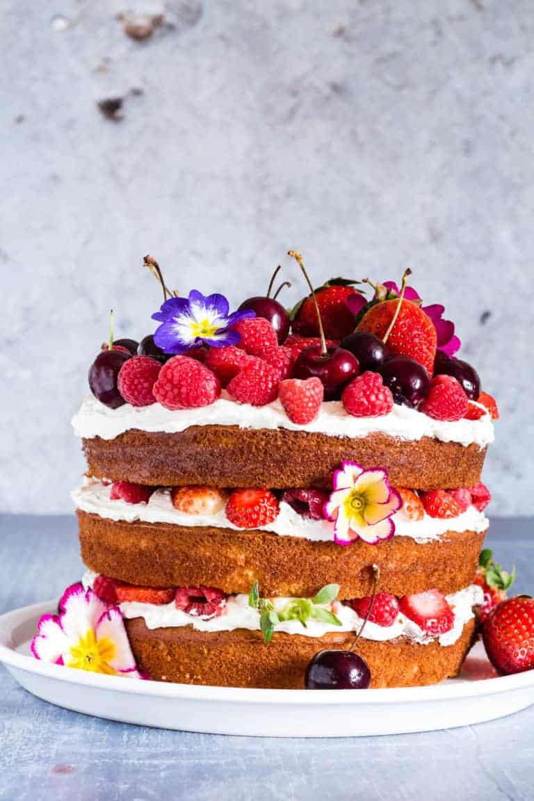 a layer cake - berry, orange blossom and elderflower cake with mascarpone cream topped with berries and flowers