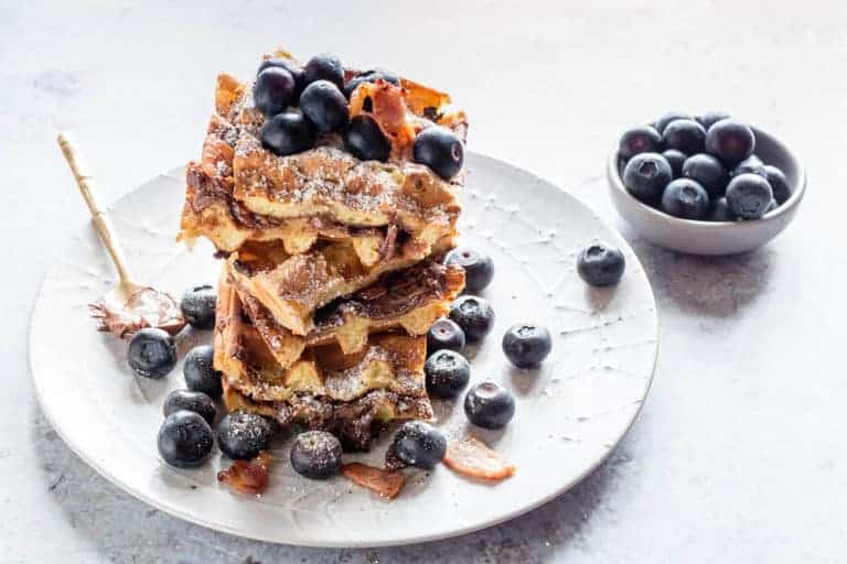 These crispy bacon Nutella stuffed waffles make an amazing breakfast or brunch recipe. Add blueberries and maple syrup for an extra treat | Recipes From A Pantry