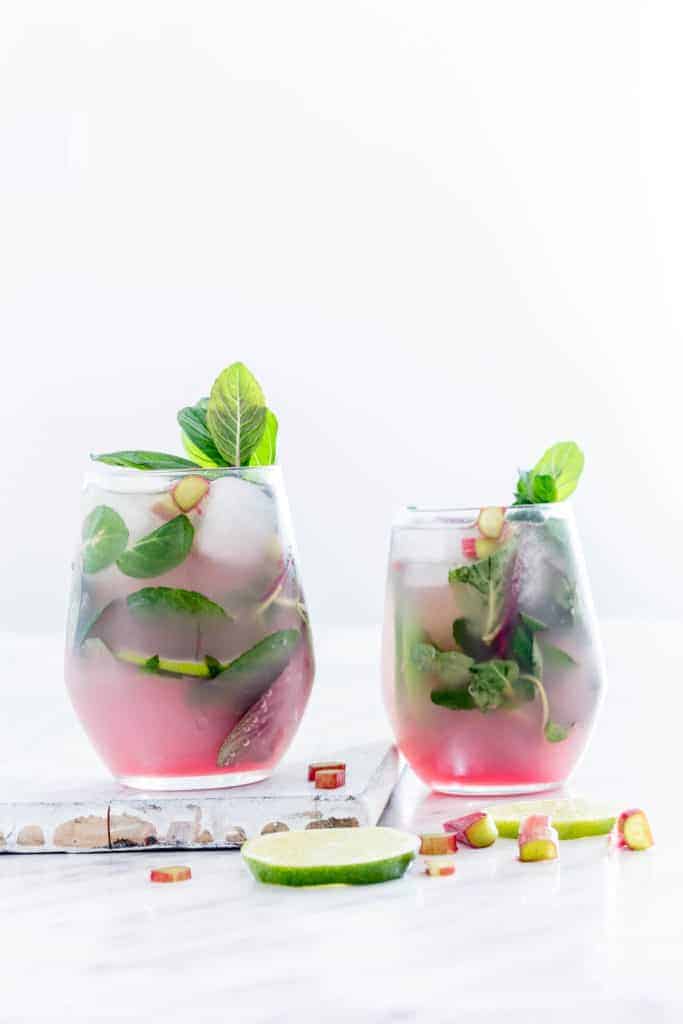 2 glasses of cold Rhubarb Mojitos -with rhubarb and lime slices