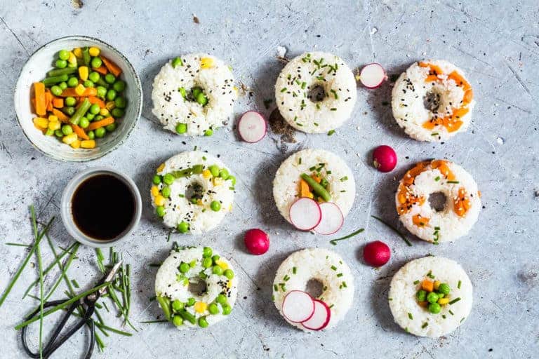 Vegetable Sushi Doughnuts on a table with a bowl of mixed vegetables and soy sauce