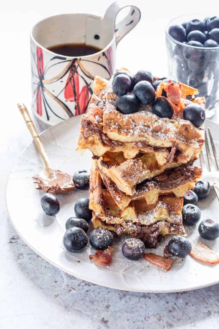 These crispy bacon Nutella stuffed waffles make an amazing breakfast or brunch recipe. Add blueberries and maple syrup for an extra treat | Recipes From A Pantry