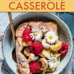 french toast casserole in a bowl garnished with raspberries and cashews.