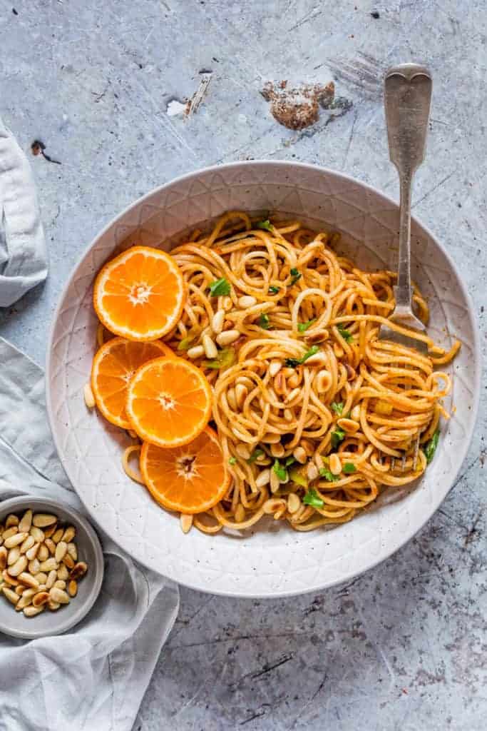 A bowl of Harissa Pasta With Oranges and pine nuts and a fork - recipesfromapantry.com