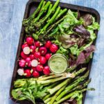 overhead view of keto snacks fresh vegetables with a dipping sauce on a large pan