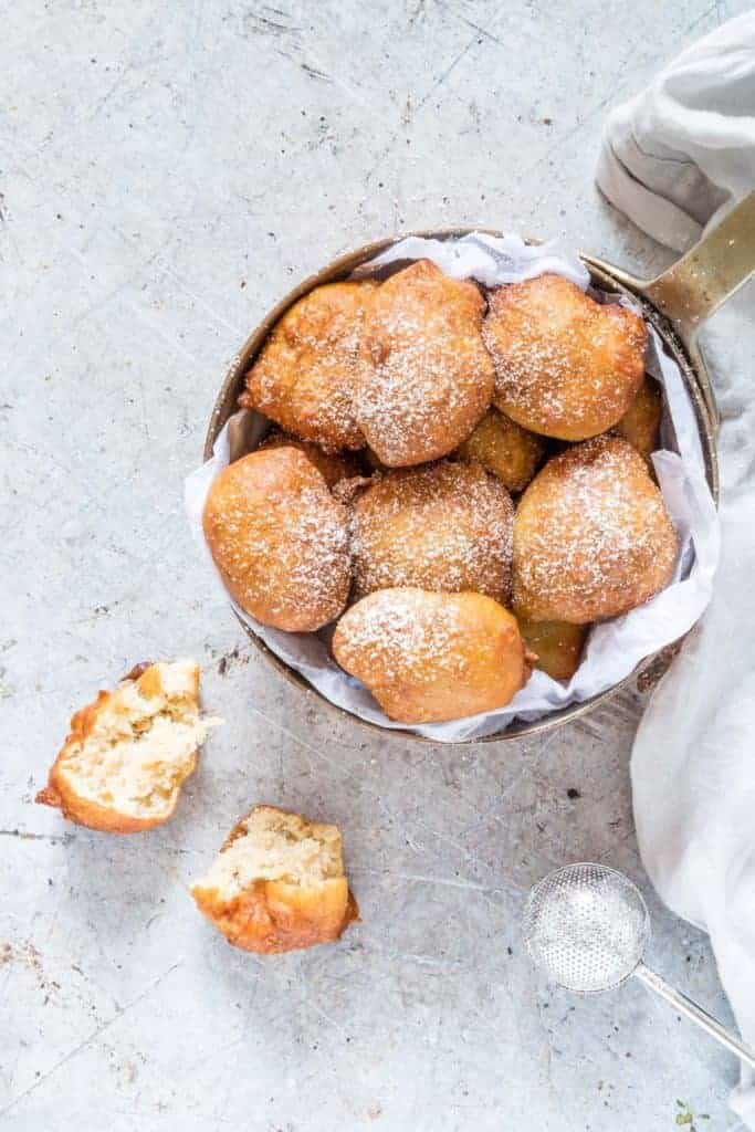 Golden Puff puff in a pan, dusted with some icing sugar and on puff puff split in half