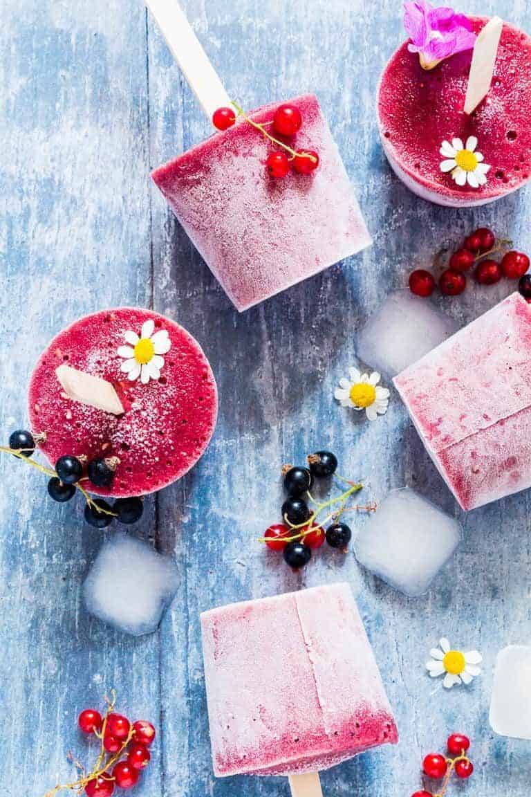 strawberry watermelon popsicles on a table with fruits and flowers