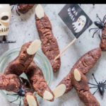 chocolate cookies shaped like witches fingers surrounded by plastic spiders