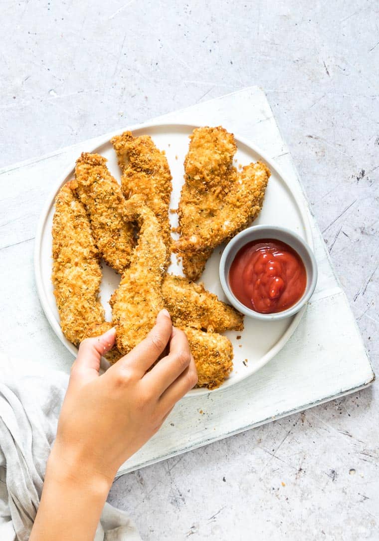 hand reaching for a parmesan crusted chicken tender