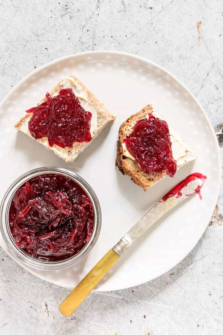 white plate with beetroot relish and two slices of bread with relish and butter