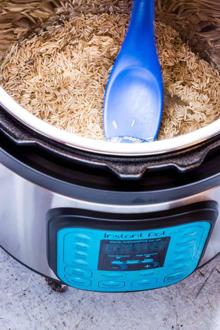  Instant Pot Brown Rice - basmati brown rice and water in an Instant Pot with a blue spoon