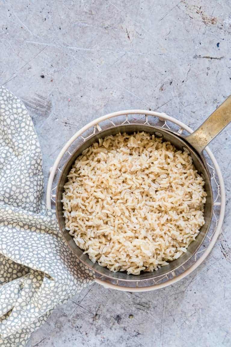 Instant Pot Brown Rice in a pot with a fork and a spotty cloth on a trivet