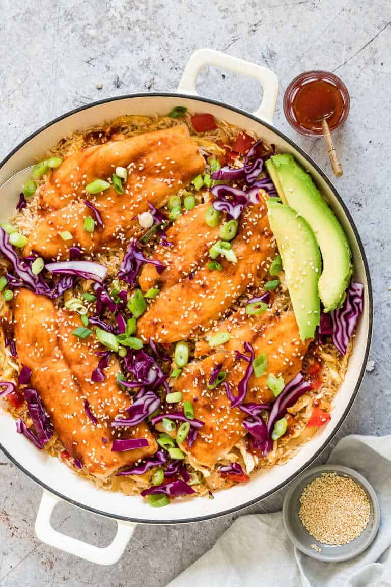 large pot filled with one pot asian rice and fish with avocado slices on top with chilli and sesame seeds